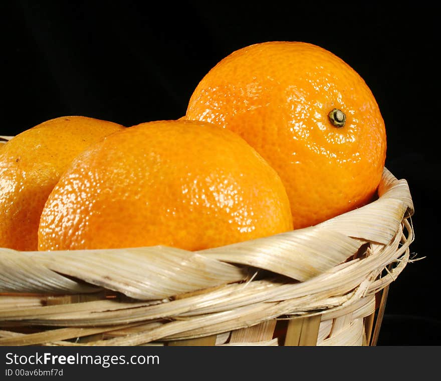 Clementines imported from Spain in a basket on a black background. These are also knows as Satsumas and are grown in southern Louisiana.