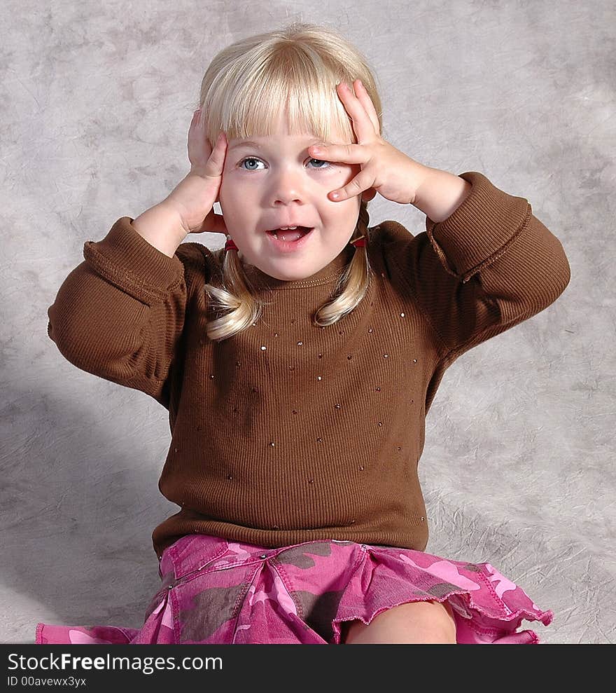 A cute little girl posing on a gray background. A cute little girl posing on a gray background.