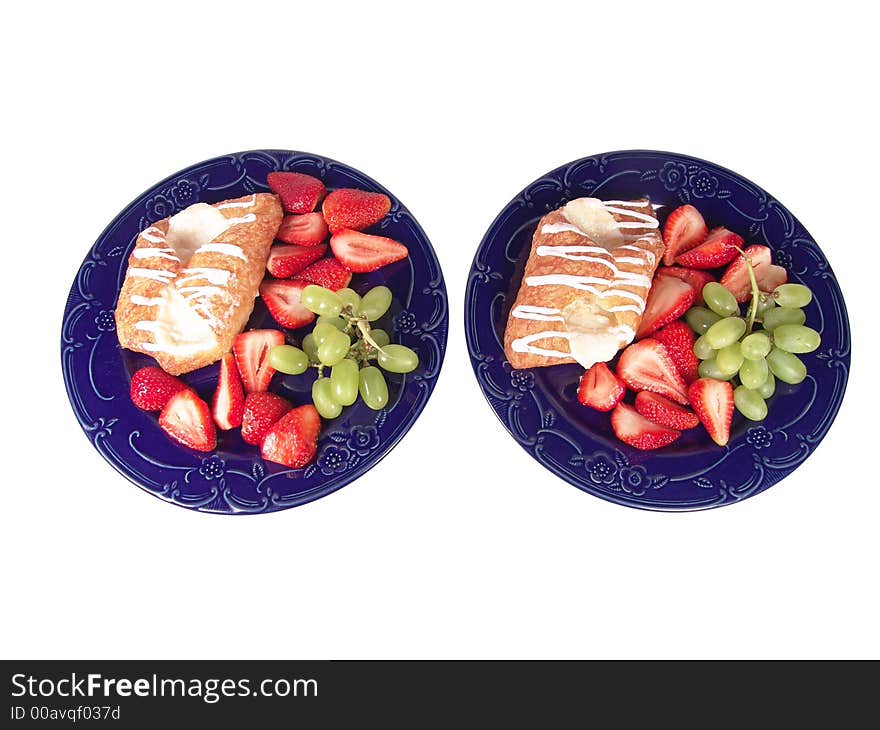 Pastry, grapes and strawberry on two blue plates