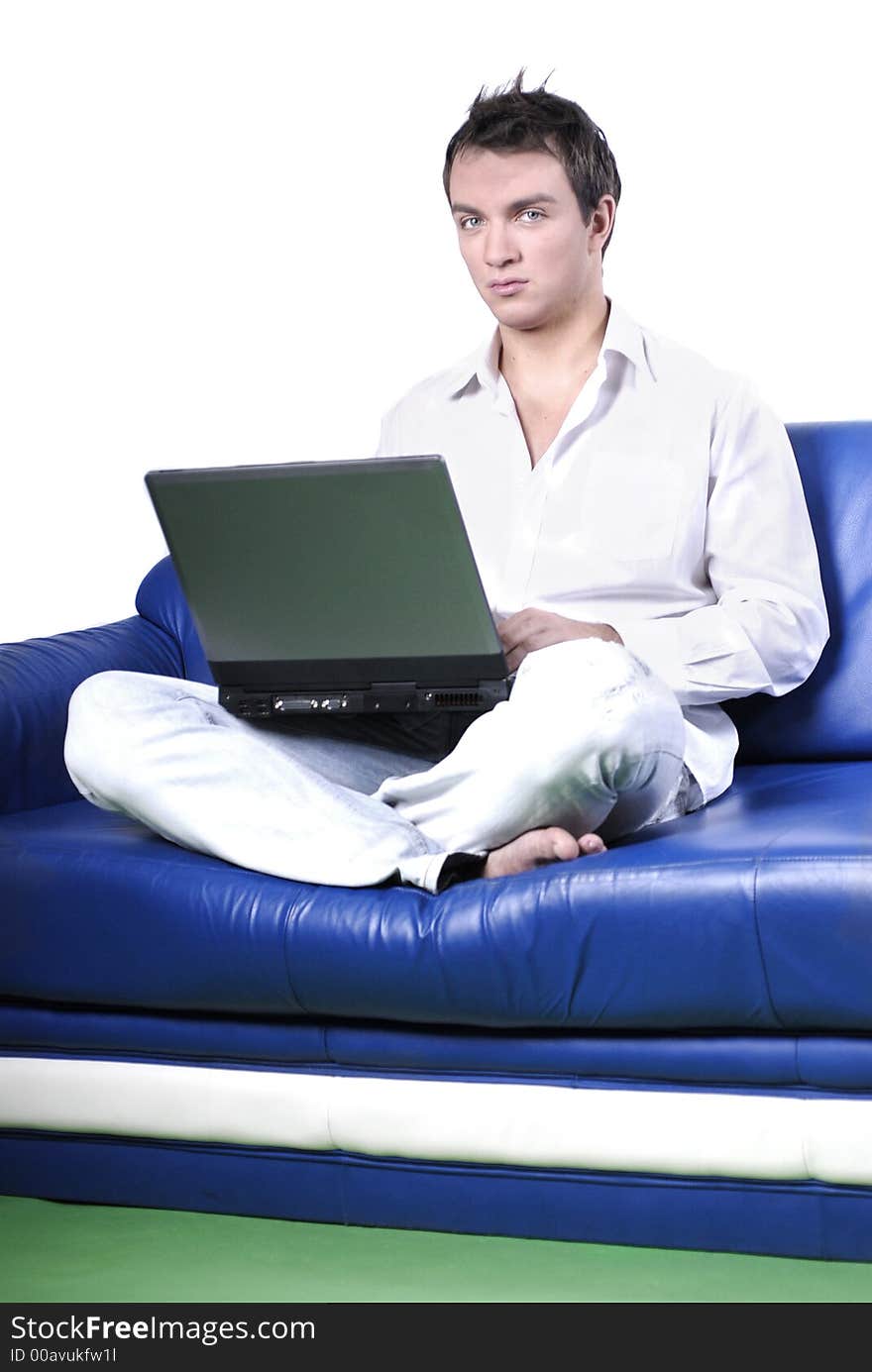 Young man comfortably sitting in a sofa using a laptop. Young man comfortably sitting in a sofa using a laptop