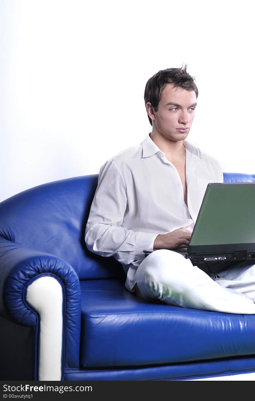 Young man comfortably sitting in a sofa using a laptop. Young man comfortably sitting in a sofa using a laptop