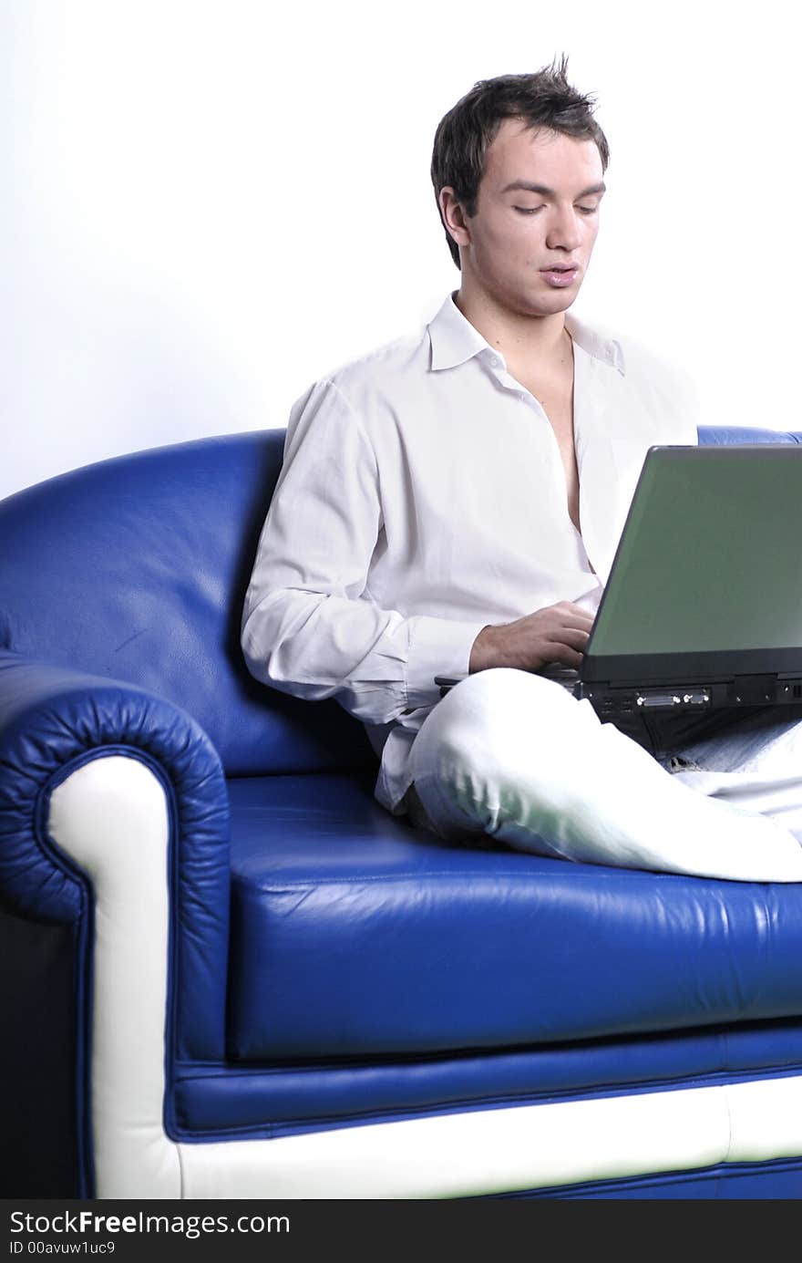 Young man comfortably sitting in a sofa using a laptop. Young man comfortably sitting in a sofa using a laptop