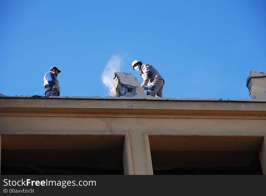 Two men working on the roof of an old building in teh center of the city. Two men working on the roof of an old building in teh center of the city