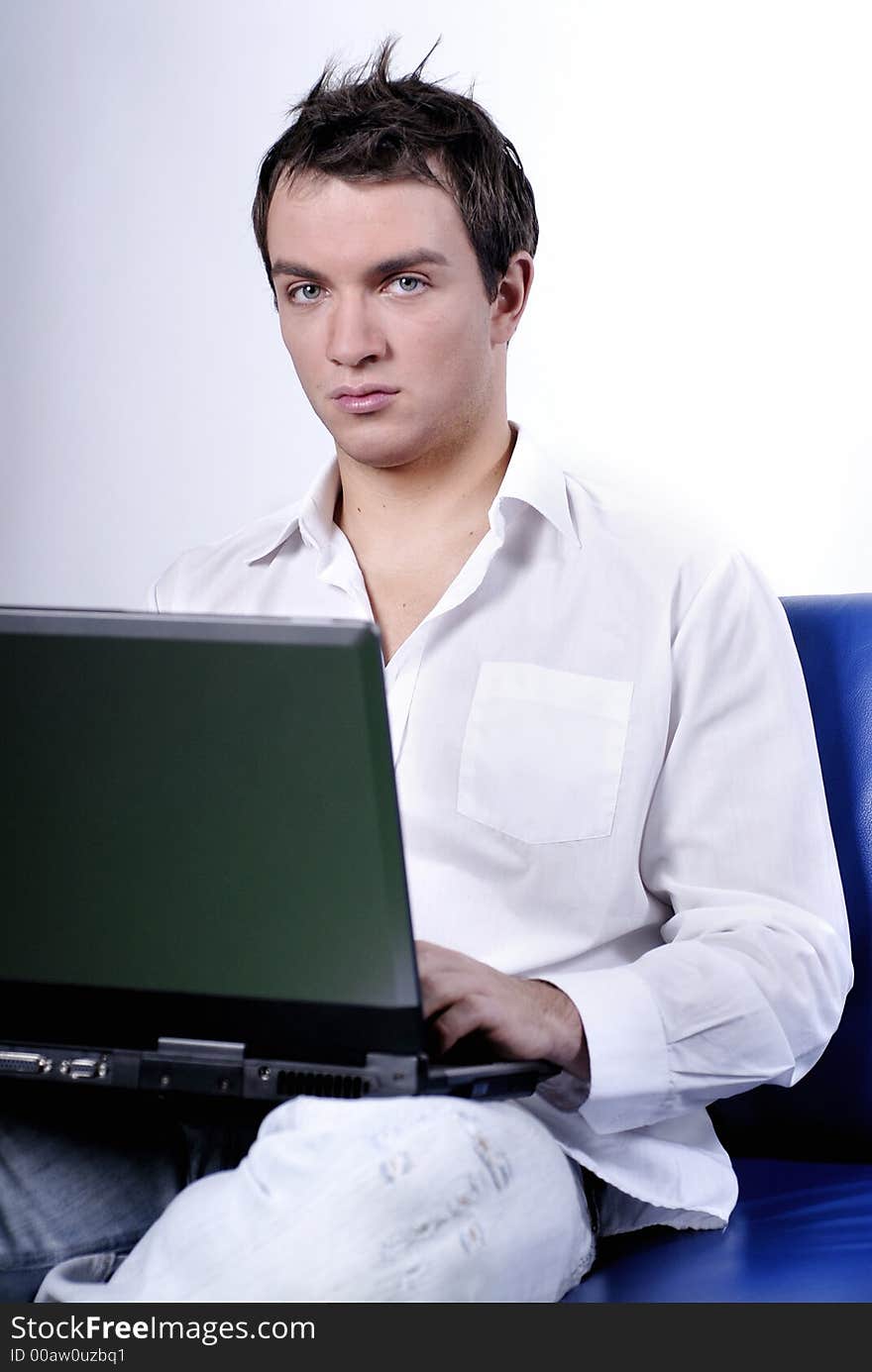 Young man comfortably sitting in a sofa using a laptop. Young man comfortably sitting in a sofa using a laptop