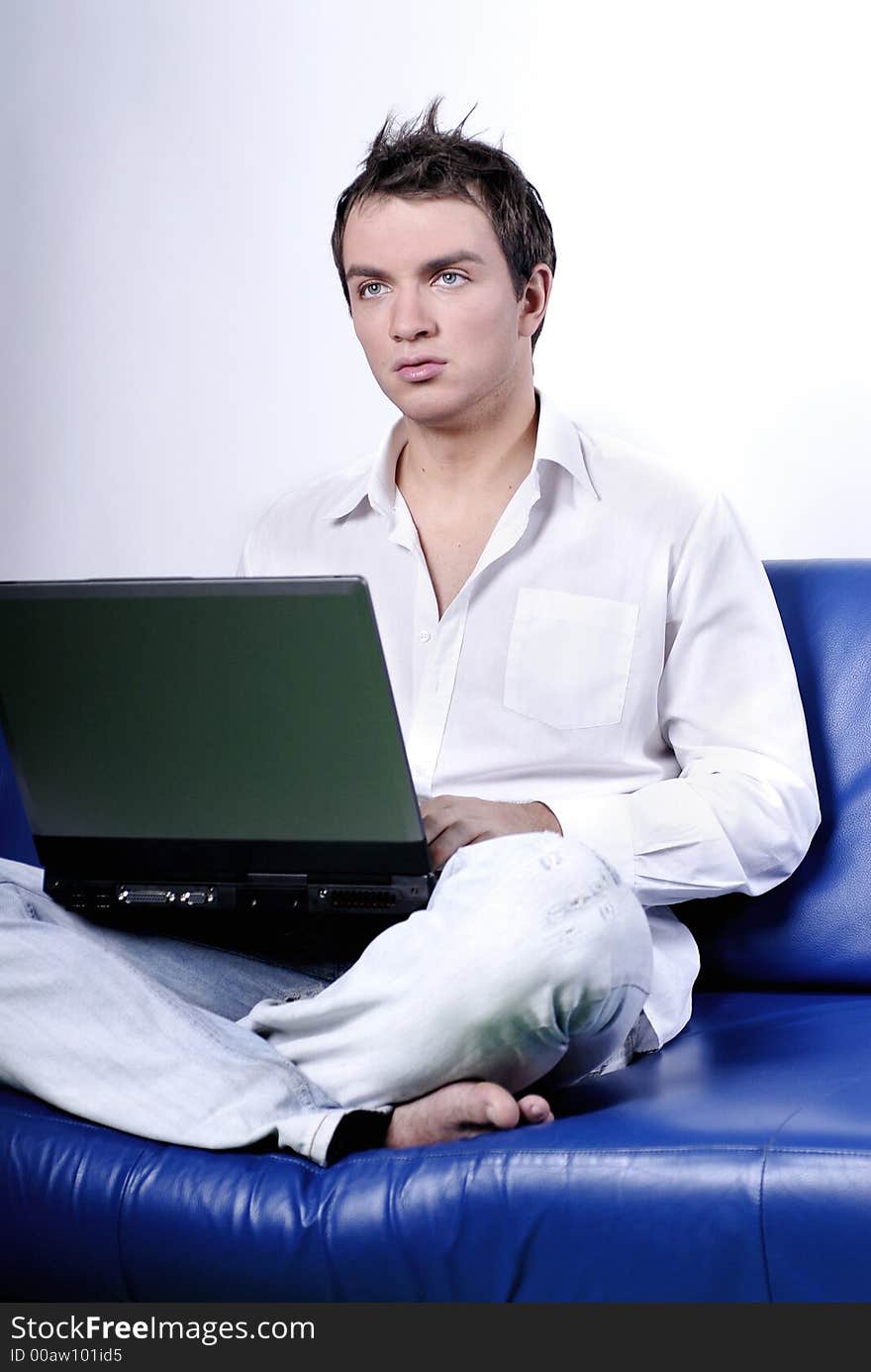 Young man comfortably sitting in a sofa using a laptop. Young man comfortably sitting in a sofa using a laptop