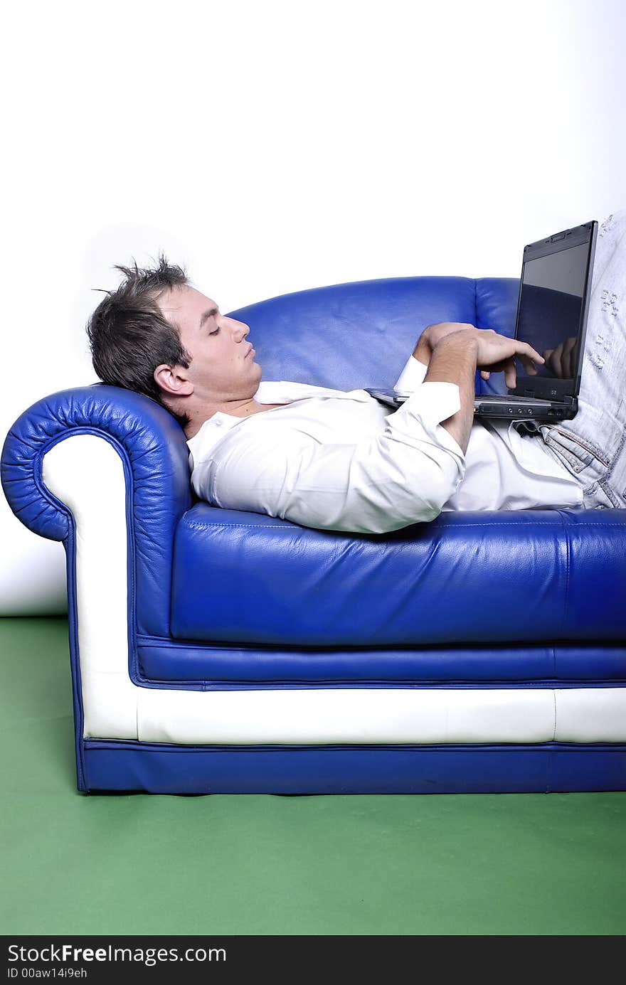 Young man comfortably sitting in a sofa using a laptop. Young man comfortably sitting in a sofa using a laptop