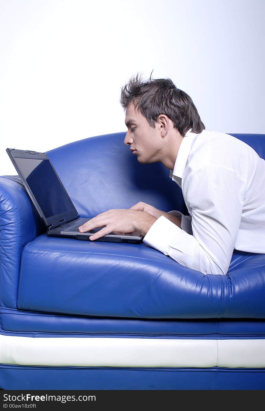 Young man comfortably sitting in a sofa using a laptop. Young man comfortably sitting in a sofa using a laptop