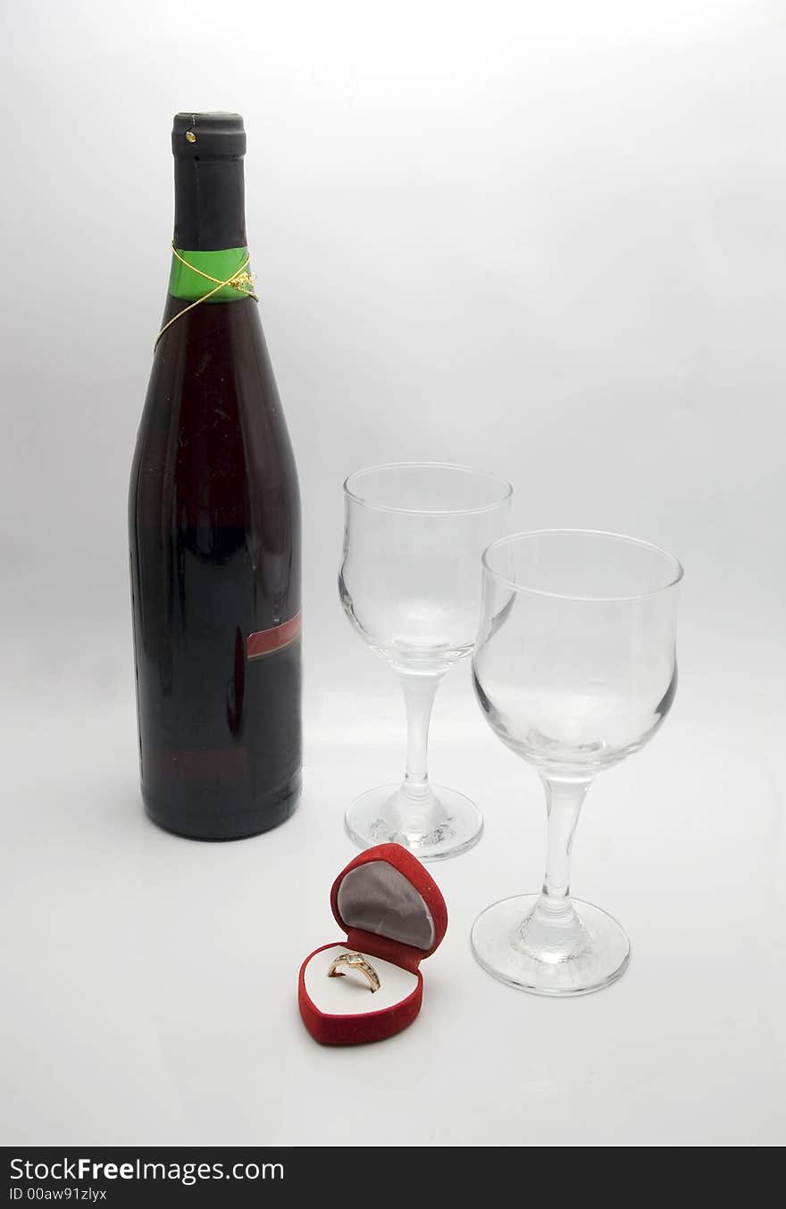 Wedding ring in a heart shaped box with glasses and a bottle of red wine. Wedding ring in a heart shaped box with glasses and a bottle of red wine