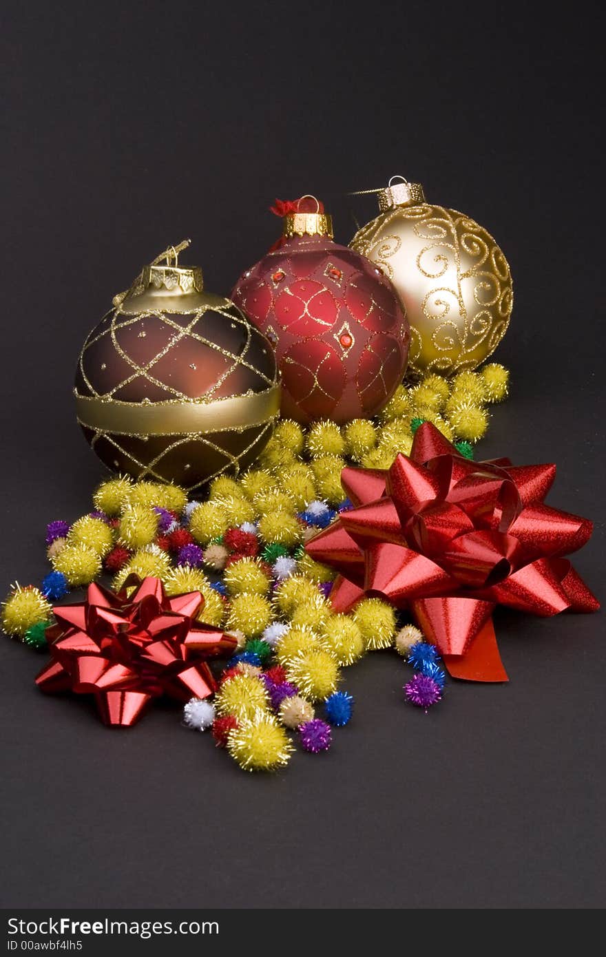 Detail of Christmas balls with bows and gold spike balls against a plain background.