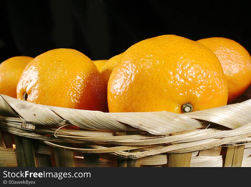 Clementines imported from Spain in a basket on a black background.  These are also knows as Satsumas and are grown in southern Louisiana.