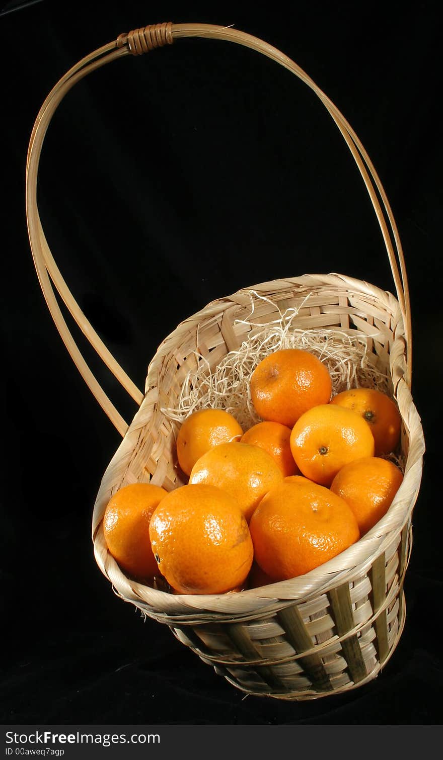 Clementines imported from Spain in a basket on a black background.  These are also knows as Satsumas and are grown in southern Louisiana.