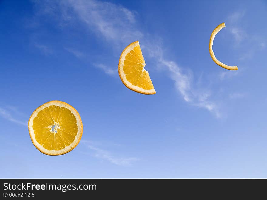 Orange slices at different stages of consumption on a blue sky background. Orange slices at different stages of consumption on a blue sky background