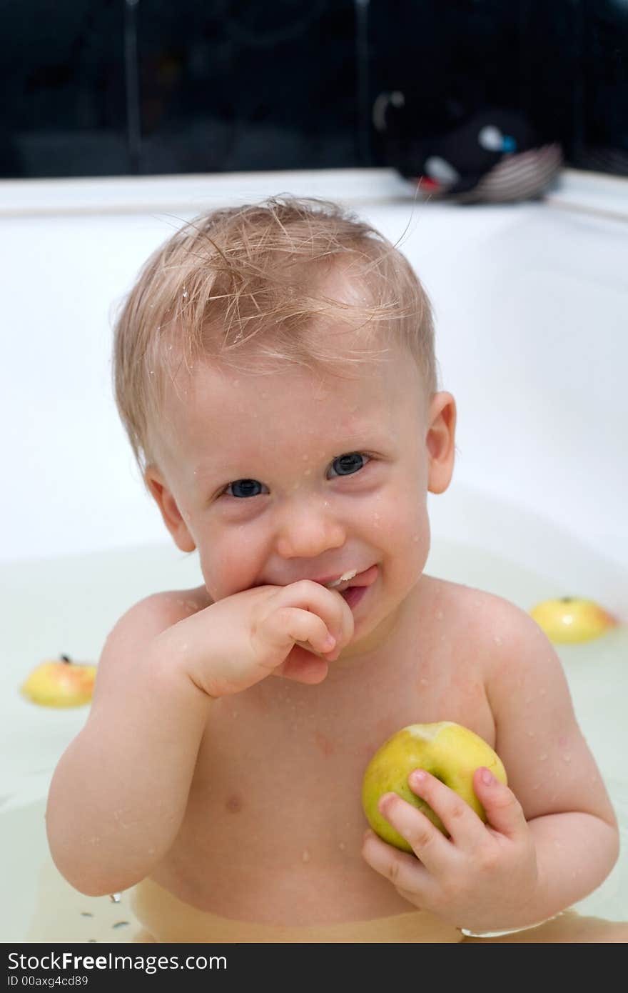 Cute little boy in the bath eating apple