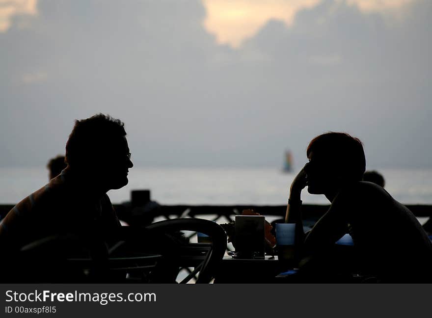 Man and woman looking at each other in front of the sea at dusk. Man and woman looking at each other in front of the sea at dusk