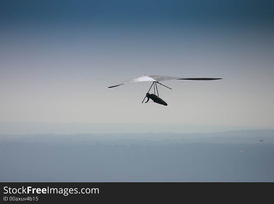 Hang glider soaring in blue sky.