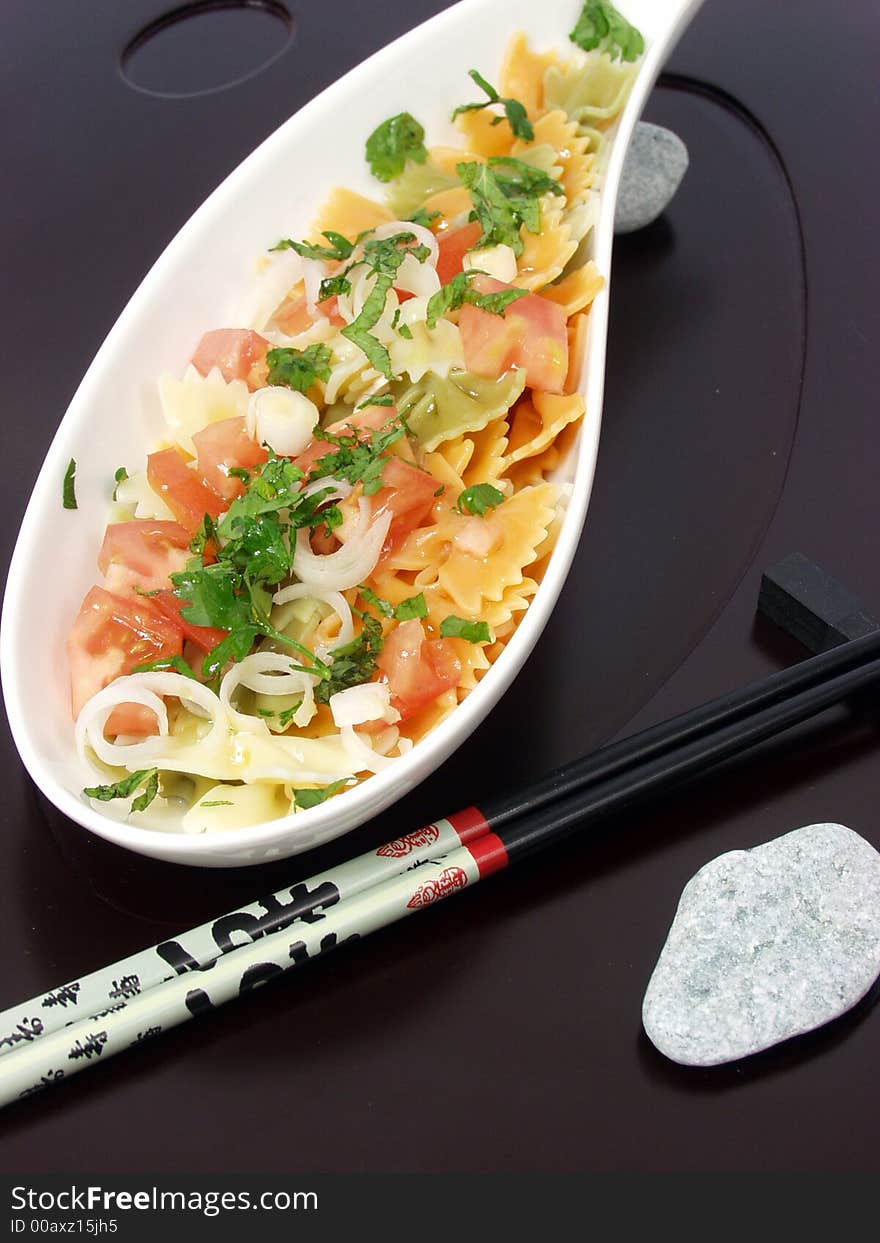 Pasta salad on white bowl with stone decoration