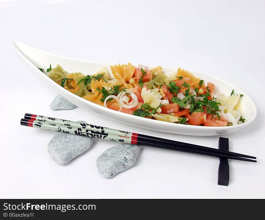 Pasta salad on white bowl with stone decoration