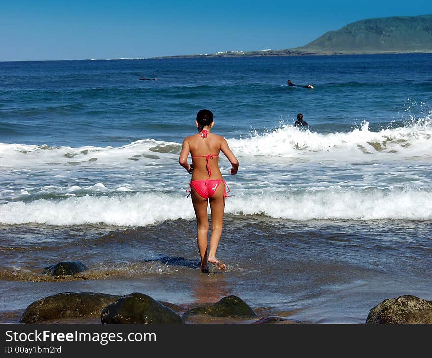 Beautiufl girl in a red bikini running into the ocean