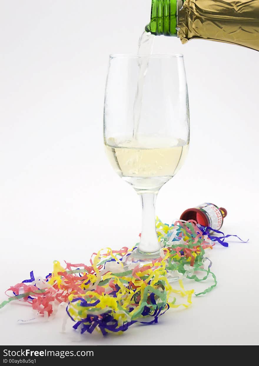 Photo of champagne being poured into a glass with confetti streamers around it. Photo of champagne being poured into a glass with confetti streamers around it