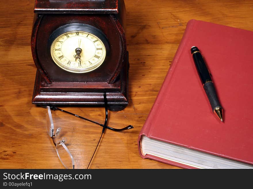 This is an image of a clock and book on a wooden desktop. This is an image of a clock and book on a wooden desktop.