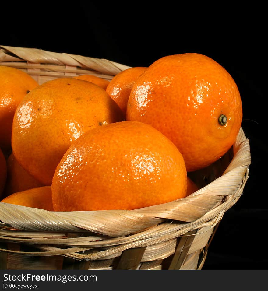 Clementines imported from Spain in a basket on a black background.  These are also knows as Satsumas and are grown in southern Louisiana.