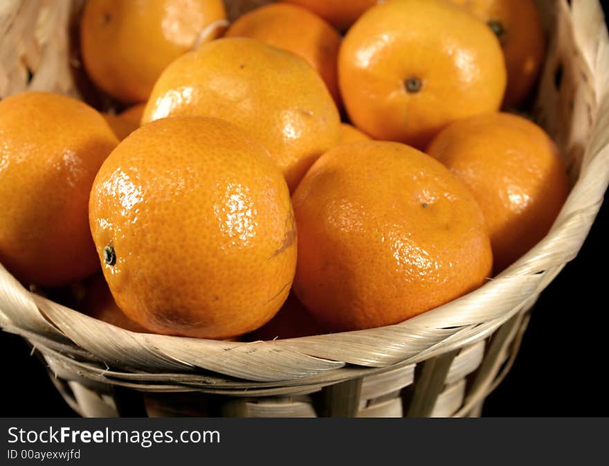 Clementines imported from Spain in a basket on a black background. These are also knows as Satsumas and are grown in southern Louisiana.