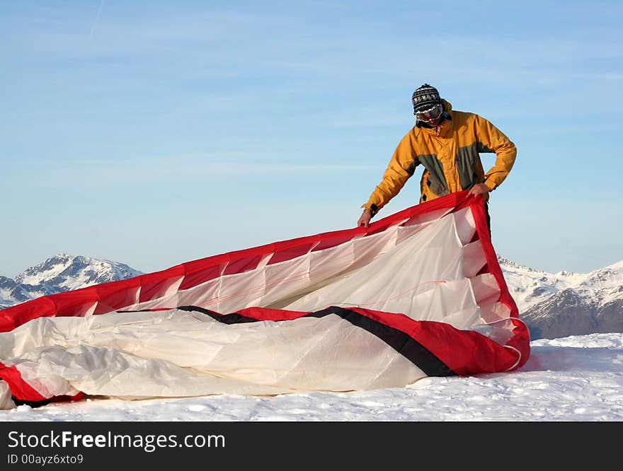 Paraglider prepares the parachute befor he paraglides over the mountains. Paraglider prepares the parachute befor he paraglides over the mountains