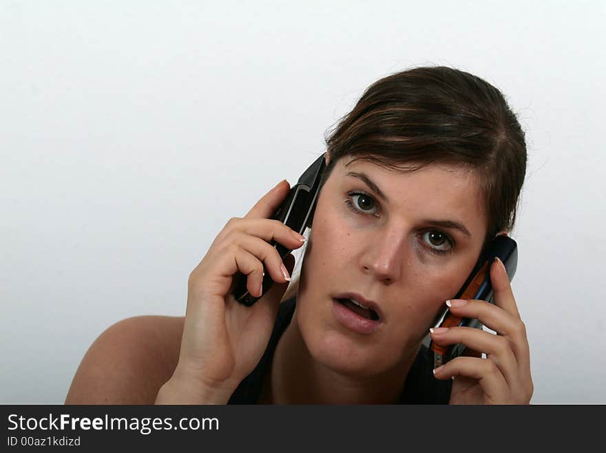 A young woman speaking on two phones being stressed.