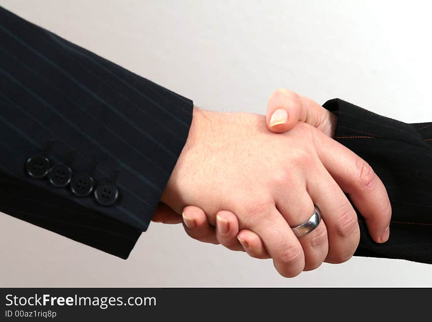 Two business people (male and female) perform a handshake. Two business people (male and female) perform a handshake.