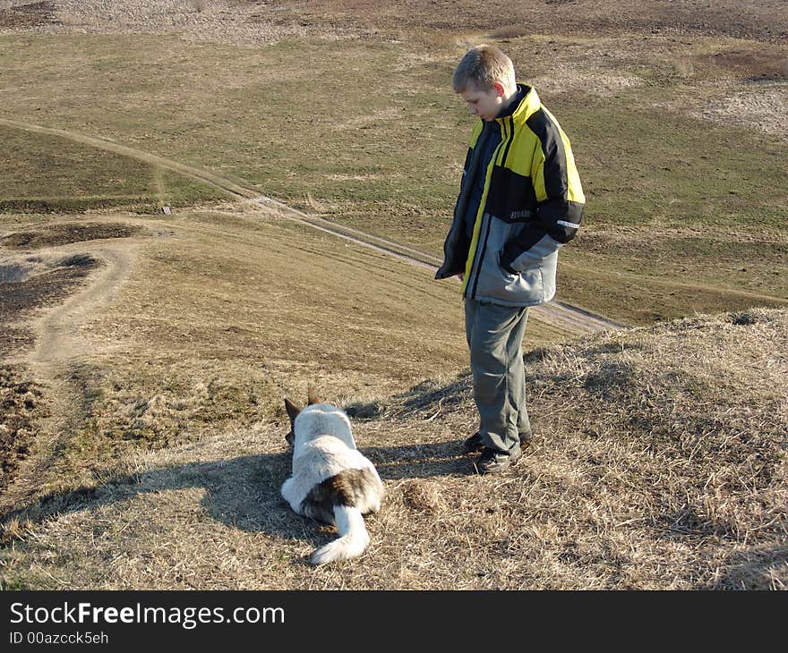 The teenager and its dog at top of a hill. The teenager and its dog at top of a hill