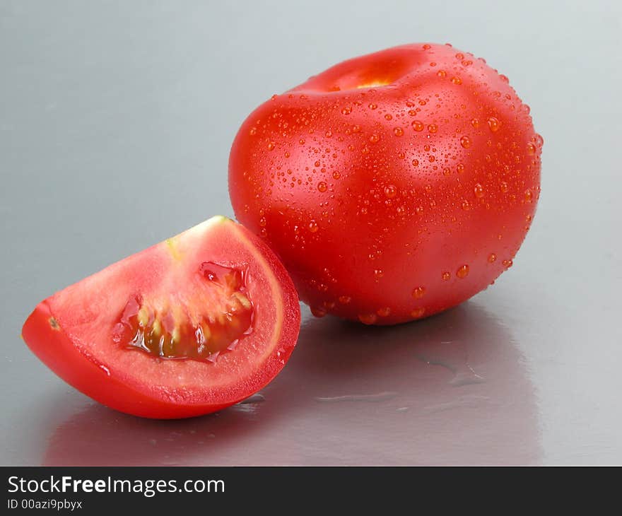 Some tomatoes whith waterdrops on a grey background. Some tomatoes whith waterdrops on a grey background