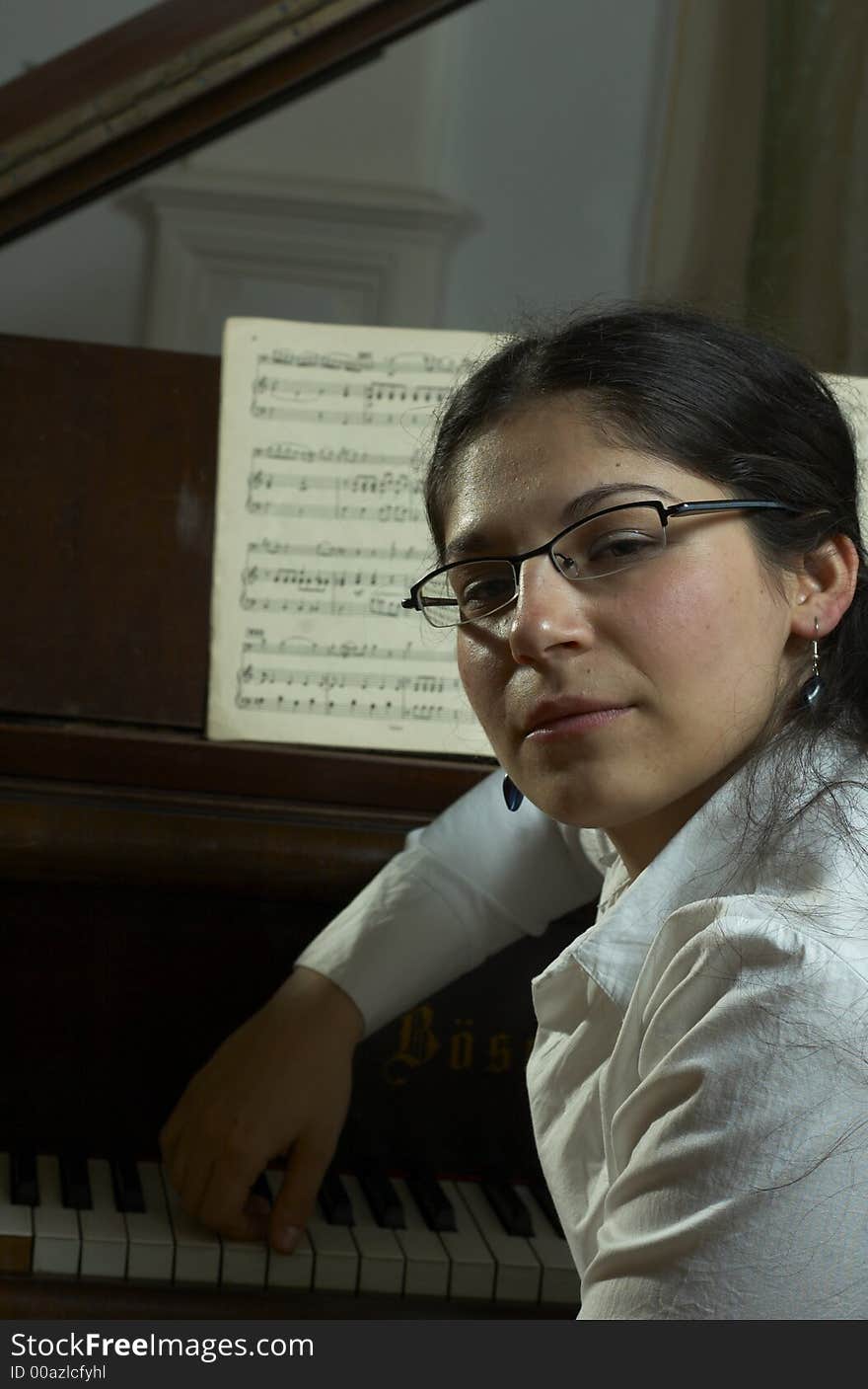 A portrait of a well-known, prize-winning female pianist, sitting at the keyboard of an open grand piano with music in the background. A portrait of a well-known, prize-winning female pianist, sitting at the keyboard of an open grand piano with music in the background.