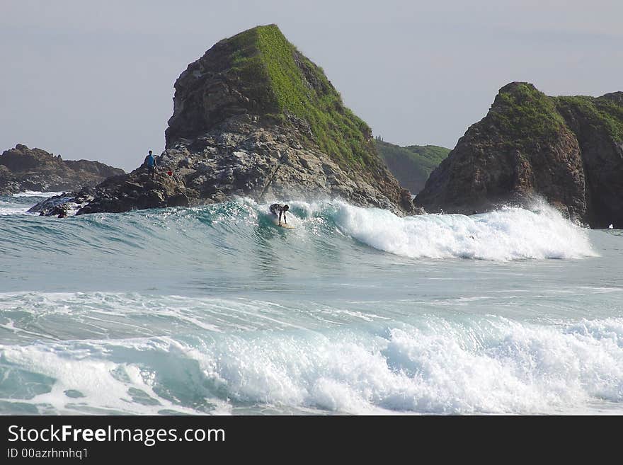 Partial view of a wave with a surfer and a small cliff in the bay of San Agustinillo in the southern state of Oaxaca in  Mexico, Latin America. Partial view of a wave with a surfer and a small cliff in the bay of San Agustinillo in the southern state of Oaxaca in  Mexico, Latin America