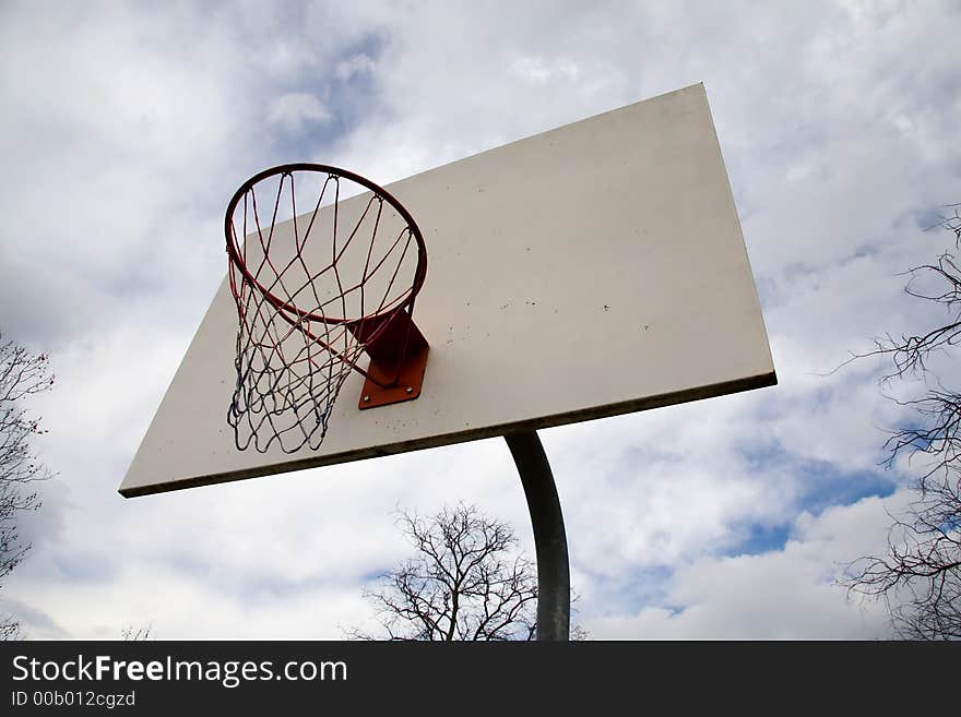 White basketball backboard and hoop with net, blue sky in background. White basketball backboard and hoop with net, blue sky in background