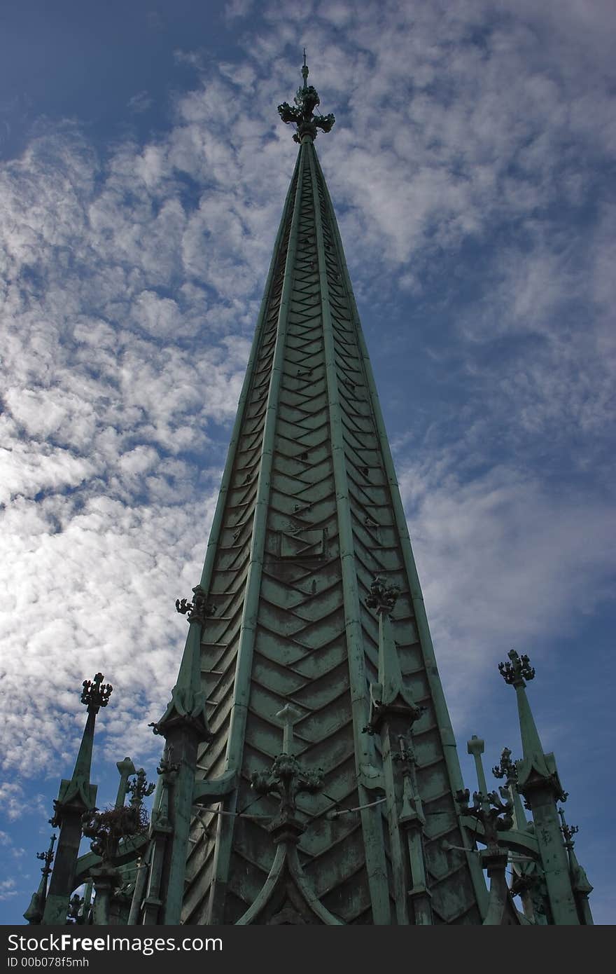 A spike of a medieval cathedral in Geneva on a background of the cloudy sky. A spike of a medieval cathedral in Geneva on a background of the cloudy sky