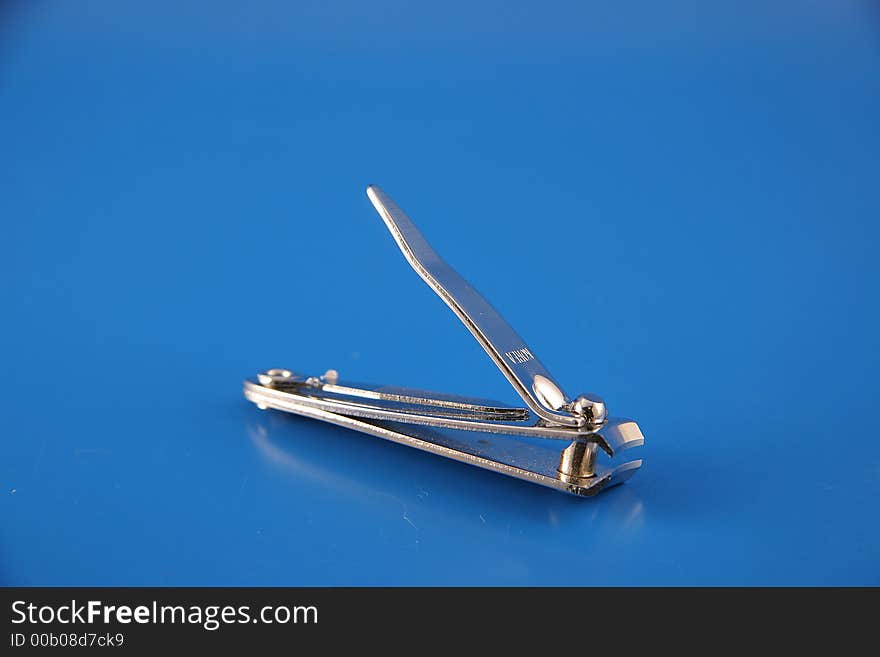 A small pair of nail clippers close up on a blue backdop. A small pair of nail clippers close up on a blue backdop.