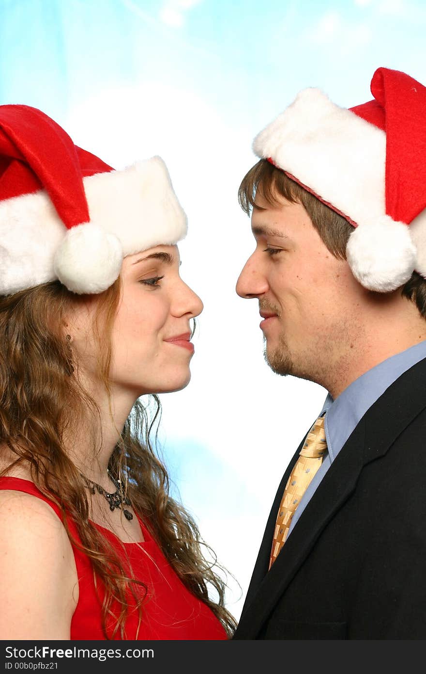 Young man and beautiful young lady with santa hats isolated on white space. Young man and beautiful young lady with santa hats isolated on white space