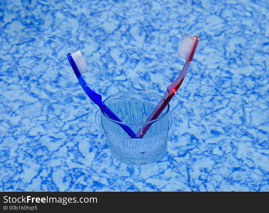 Two toothbrushes in a glass floating on water