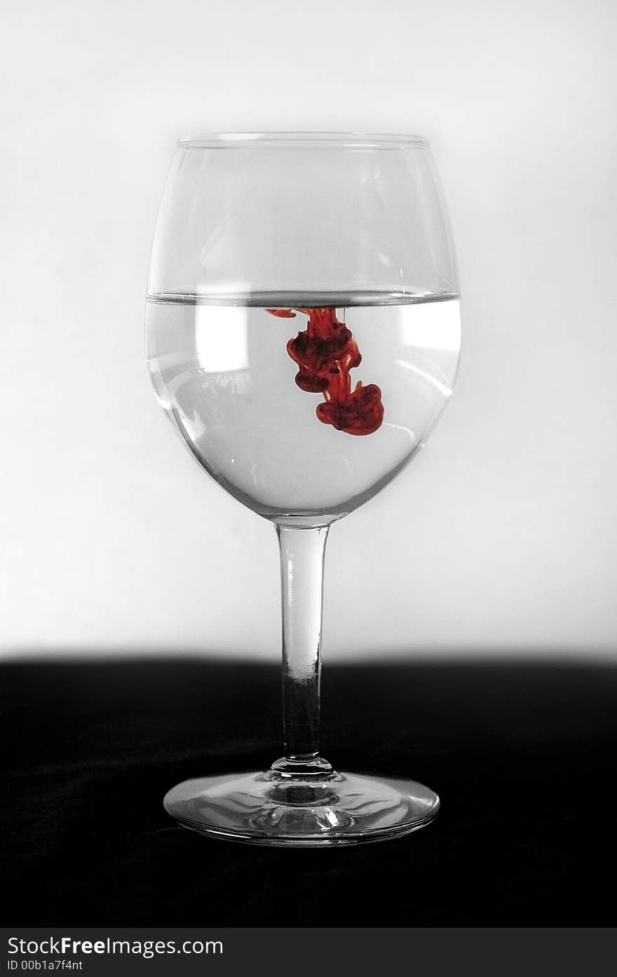 Simply, a wine glass shot on black bottom, white background, with drips of red dropped inside. Simply, a wine glass shot on black bottom, white background, with drips of red dropped inside.