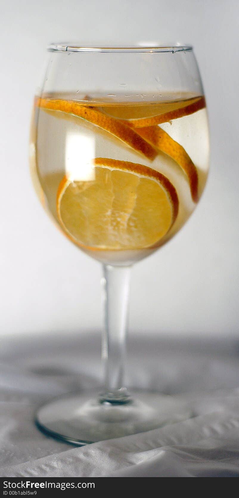 A wine glass shot with slices of tangerine inside. Shot on white background. A wine glass shot with slices of tangerine inside. Shot on white background.