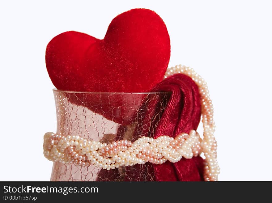 Red velvet heart in the crystal vase with piece of red velvet and pearl beads. Isolated on white background.