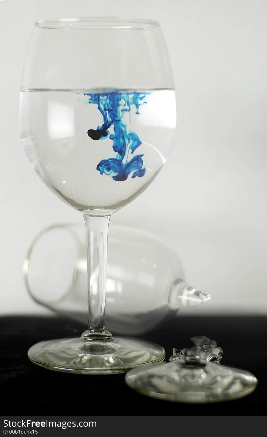 Simply, a broken wine glass and another shot on black bottom, white background, with drips of blue dropped inside. Simply, a broken wine glass and another shot on black bottom, white background, with drips of blue dropped inside.