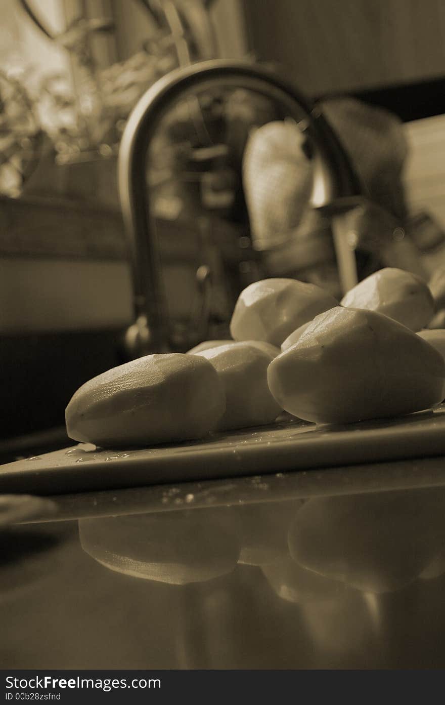 Peeled russet potatoes next to a kitchen sink shallow depth of field.  Potatoes are washed and ready for mashing. Peeled russet potatoes next to a kitchen sink shallow depth of field.  Potatoes are washed and ready for mashing.