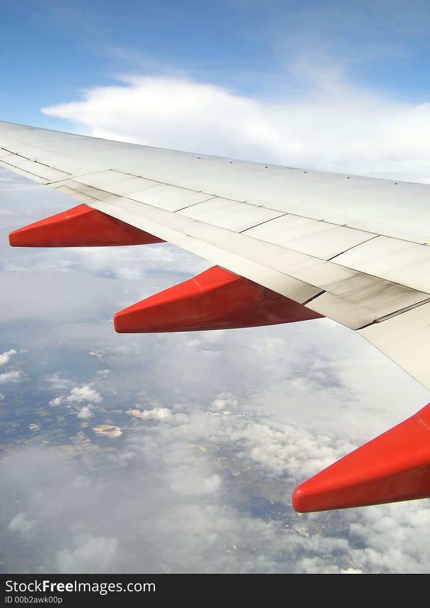 Airplane wing in flight with ground visible below. Airplane wing in flight with ground visible below