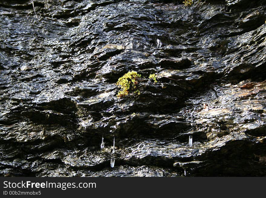 Mossy rocks on cliff with water running down