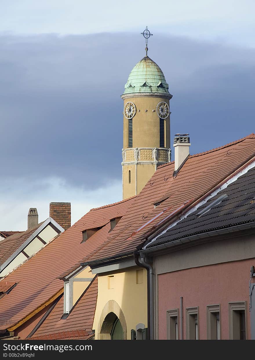 Church tower with a green rooftop behind a row of houses