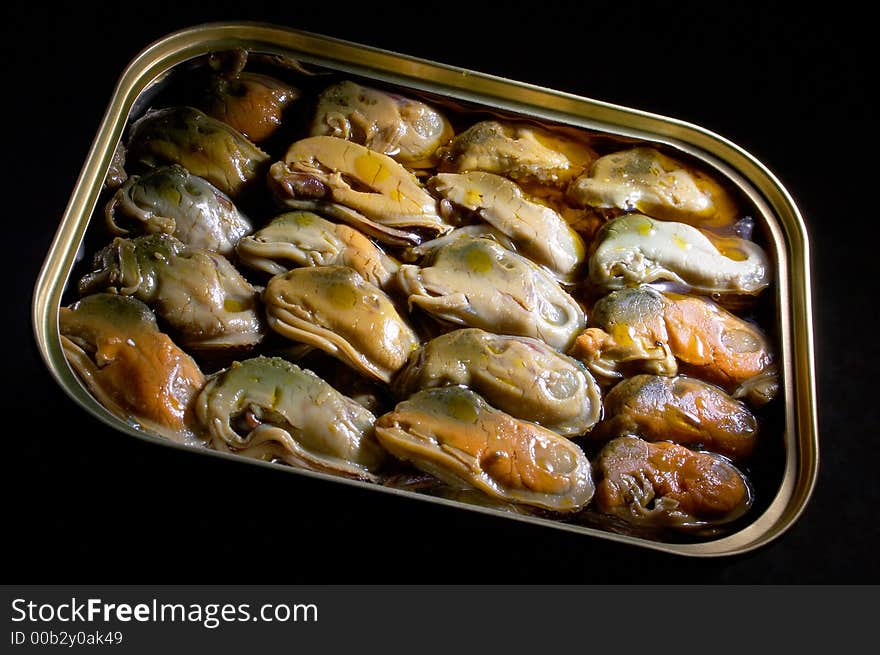 Smoked mussels in vegetable oil on a black background