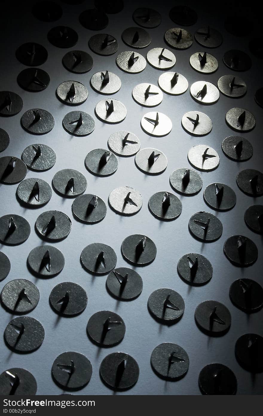 Metal drawing-pins in a ray of light