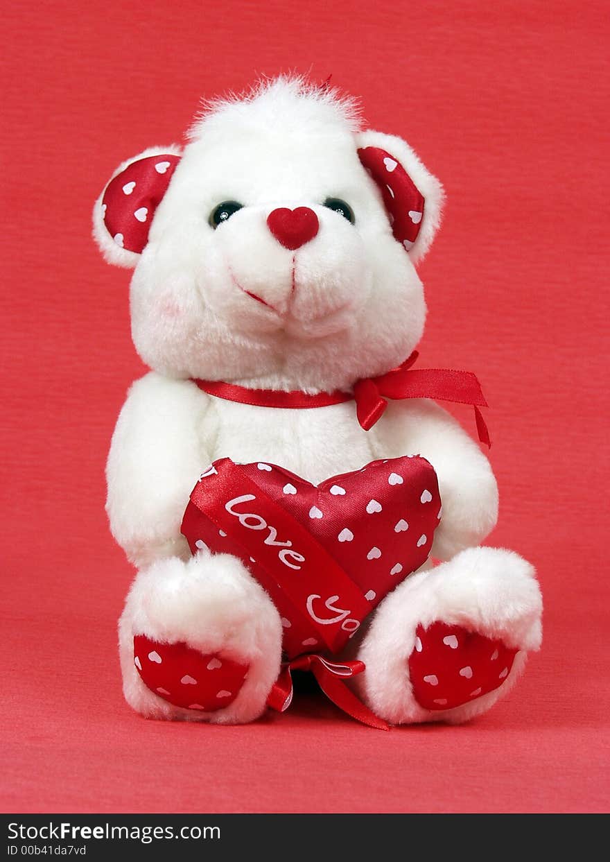 Teddy bear with red valentine heart on red background