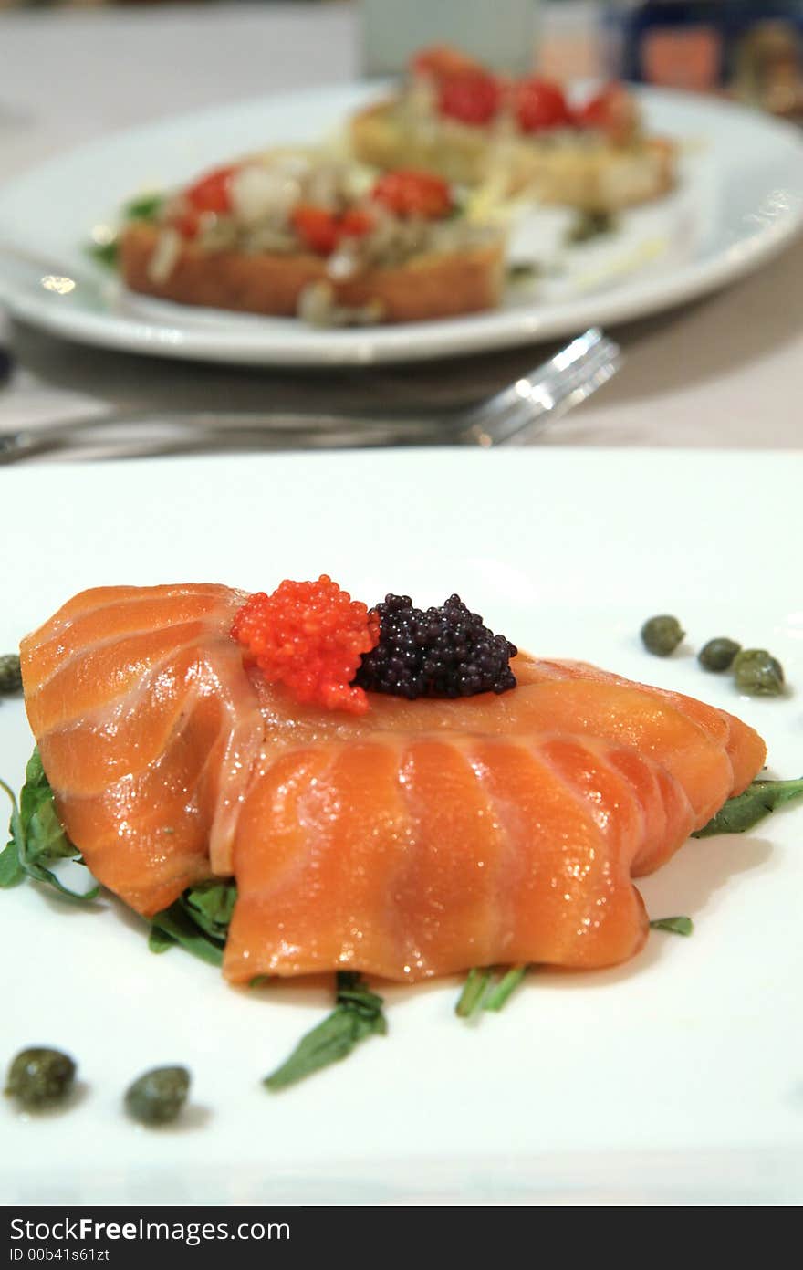 Smoked salmon slices with red and black caviar and capers